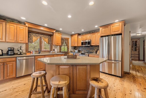 Una cocina moderna con armarios de madera, electrodomésticos de acero inoxidable y una isla central con taburetes.