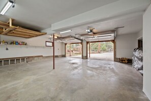 Un garaje amplio con pisos de concreto, vigas de madera y un ventanal con vistas al exterior.