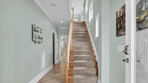 Eine Treppe mit Holzwand und beigem Teppich, die zu einem Raum mit einer weißen Tür und einem Bild an der Wand führt.