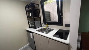 A compact kitchen with a sink, stove, and microwave. - estudio Centro (San Carlos de Bariloche)