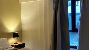 A hotel room with a bed, a nightstand, a lamp, and a view of the outside. - estudio Centro (San Carlos de Bariloche)