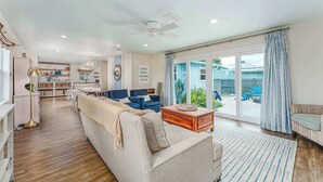 A spacious living area with a sofa, coffee table, and a view of the backyard through large sliding glass doors. - Tranquil home w/ firepit near beach (Port St. Joe)