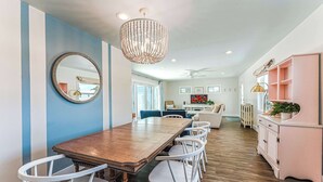 A dining area with a wooden table, white chairs, a large mirror, and a chandelier. - Tranquil home w/ firepit near beach (Port St. Joe)