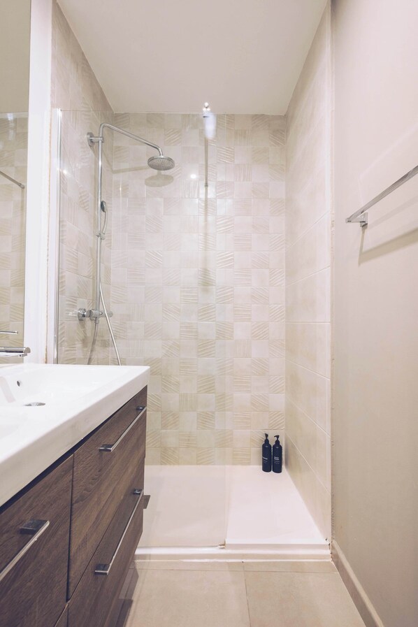 Un baño moderno con ducha, tocador con espejo y retrete.