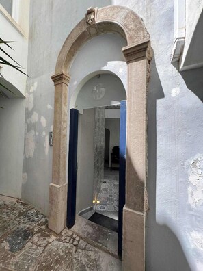 An arched doorway leading into a building with a tiled floor and a patterned wall.