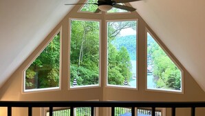 A room with a sloped ceiling, a ceiling fan, and large windows offering a view of a forested area. - Deerfield Hideaway At Old Rocky 5 Bedroom Home (La Follette)