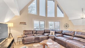 A spacious living room with a large sectional sofa, a wooden coffee table, and a TV stand. - Deerfield Hideaway At Old Rocky 5 Bedroom Home (La Follette)