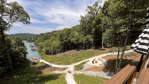 A deck overlooking a river with boats, surrounded by dense forest. - Deerfield Hideaway At Old Rocky 5 Bedroom Home (La Follette)