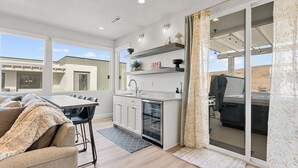 Una cocina moderna con comedor, ventanas amplias y una puerta corrediza de vidrio que da a un patio.