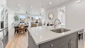 Una cocina moderna con una isla grande, electrodomésticos de acero inoxidable y vistas al salón.