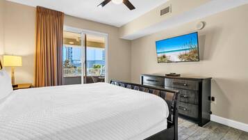 Habitación de hotel con cama, televisor, cómoda y balcón con vistas.