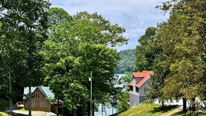 A lakeside property with two cabins, one with a red roof and another with a grey roof, surrounded by lush greenery and a clear view of the lake. - Deerfield Hideaway At Old Smokey 5 Bedroom Home (La Follette)
