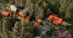 An aerial view of a resort with multiple buildings, a swimming pool, and a forested area. - L'Aiglon - Pool, Golf & Tremblant (Mont-Tremblant)