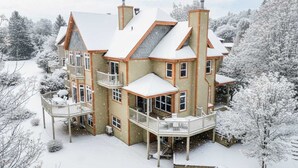 A large, multi-story house with a snow-covered roof and multiple balconies. - L'Aiglon - Pool, Golf & Tremblant (Mont-Tremblant)