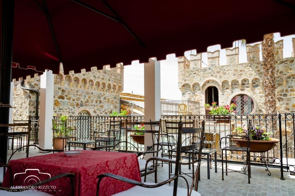 Un patio al aire libre con paredes de piedra, sillas y mesas de metal.