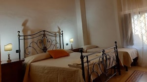 Un dormitorio con dos camas, cabeceros de madera, lámparas de noche y una ventana con cortinas.
