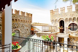 A courtyard with stone walls, a balcony with a metal railing, and potted plants. - Residenza Antico Borgo (Filadelfia)