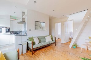 A modern kitchen with a built-in oven and a dining area with a green sofa and a small table.