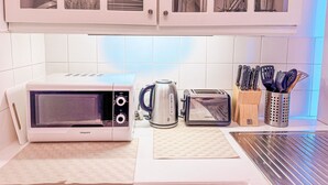 Una cocina con microondas, tostadora, hervidor y bloque de cuchillos.