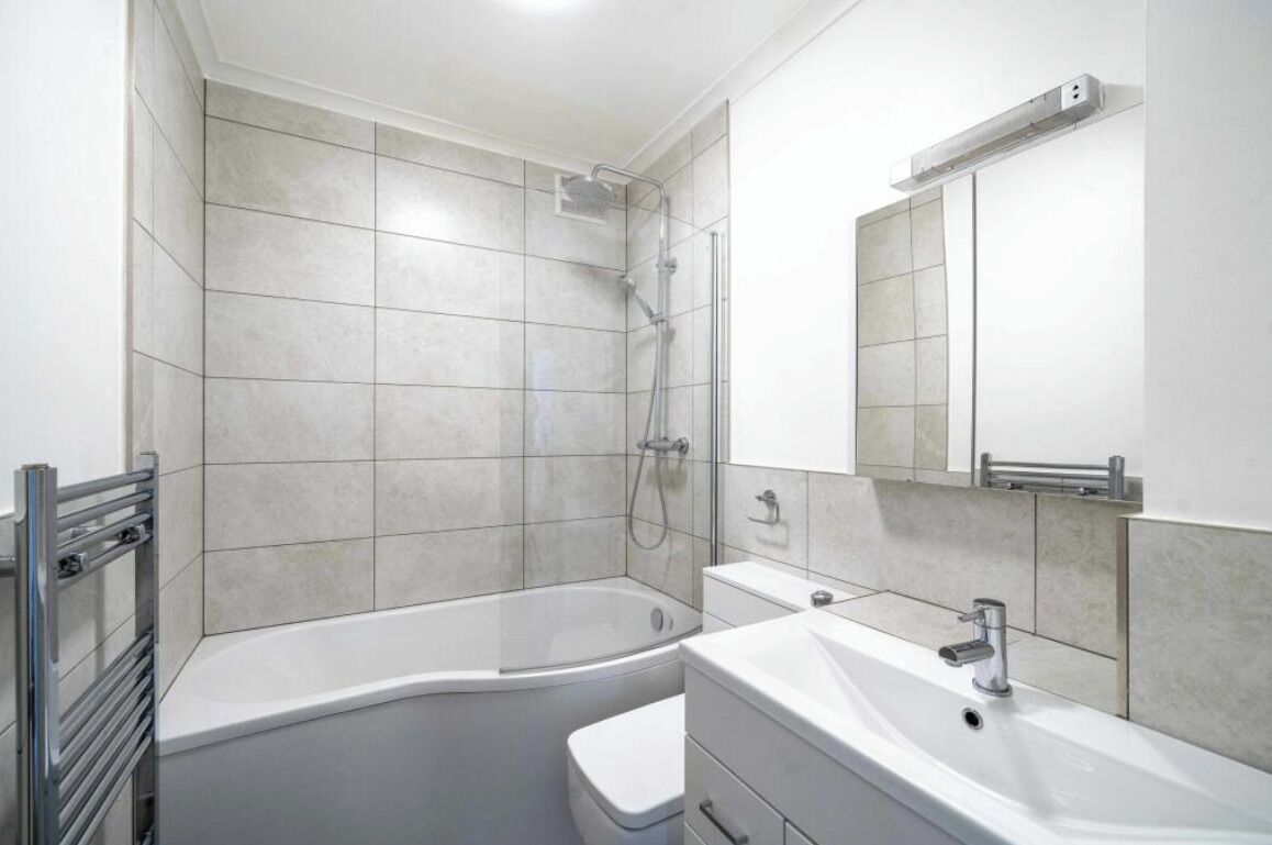 Een moderne badkamer met een badkuip, toilet, wastafel en douche.
