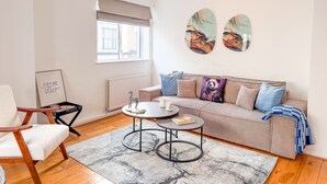 Una sala de estar moderna con un sofá, una mesa de centro, una silla y obras de arte en la pared.