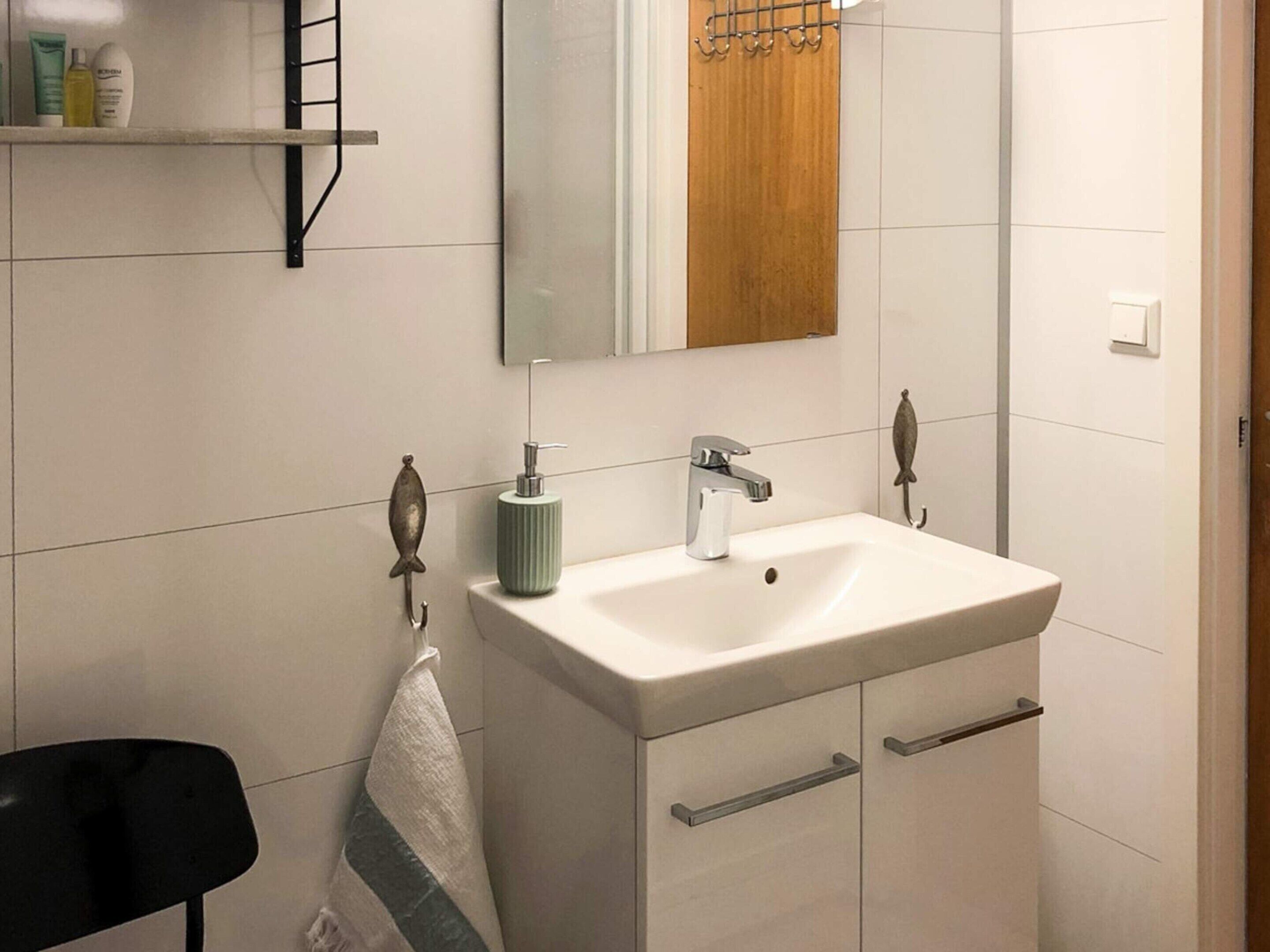 Ein Badezimmer mit einem weißen Waschbecken, einem Spiegel und einem Handtuchhalter.