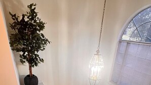 Eine Treppe führt zu einem Wohnbereich mit Holzboden, einem grünen Sofa, einem Blumentopf und einer Pendelleuchte.