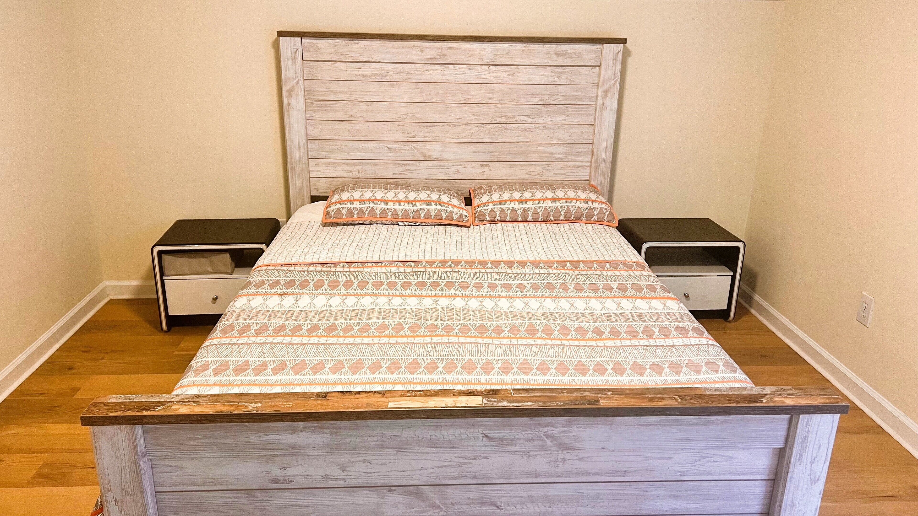 A bed with a wooden headboard, two nightstands, and a patterned bedspread.