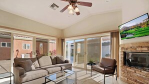 A modern living room with a sofa, coffee table, and armchair, a fireplace, and a television mounted on the wall.