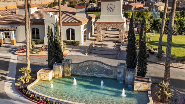 A courtyard with a fountain, palm trees, and a clock tower.