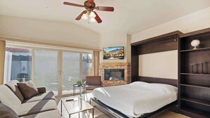 A modern bedroom with a bed, a sofa, a TV, and a fireplace.