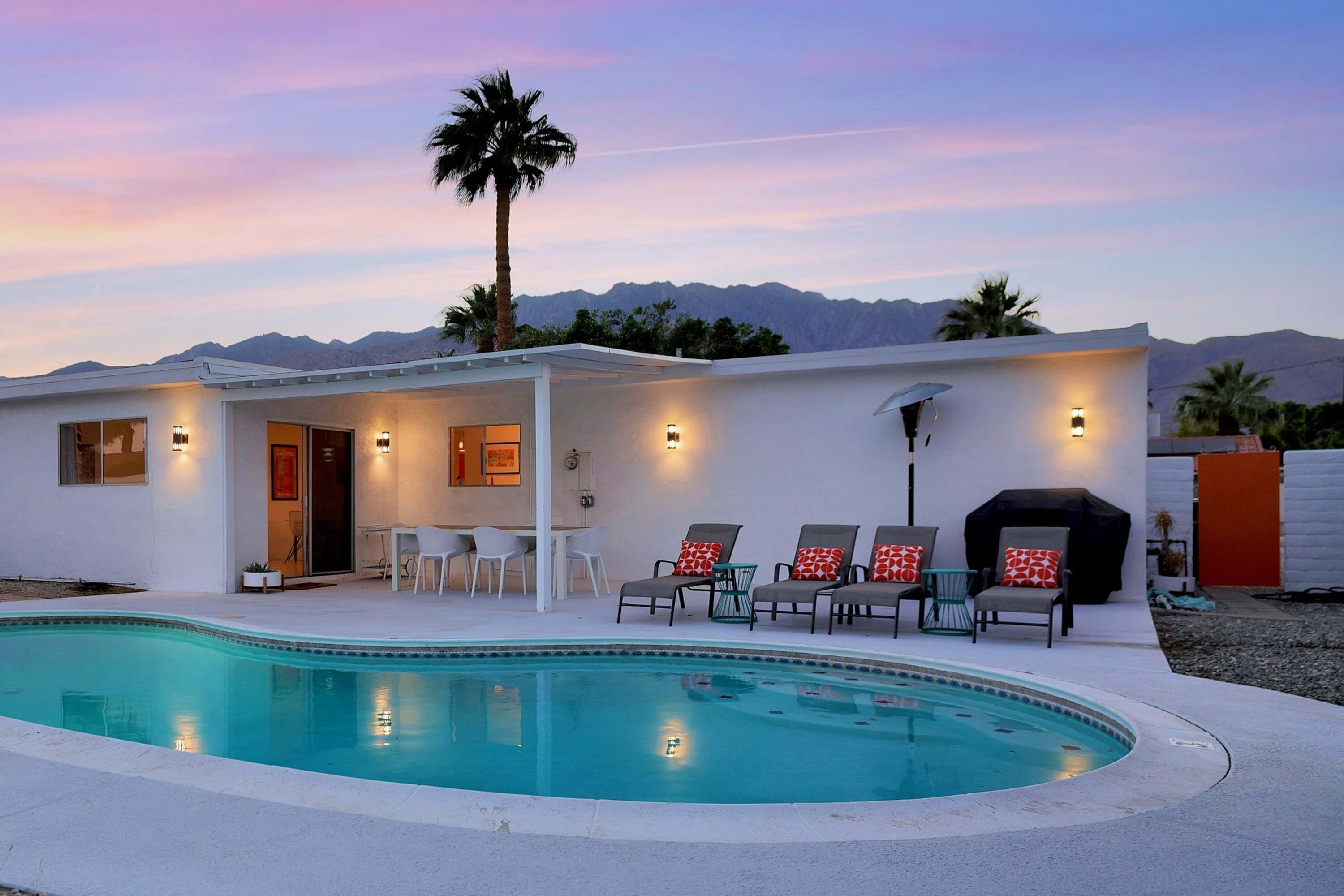 A modern house with a swimming pool, outdoor seating, and a mountain view.