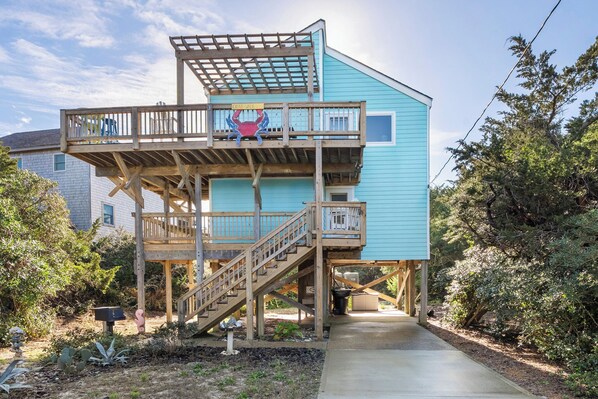 Une maison à deux étages avec une terrasse en bois et un balcon.