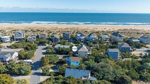 Eine Luftaufnahme einer Küstenwohngegend mit Häusern, einer Straße und einem Strand im Hintergrund.