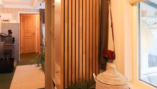 A hallway with a wooden door, a wicker basket, and a window with a view. - 6 Person Holiday Home in Sondeled (Risør)