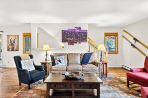 Un salon avec un canapé, des fauteuils, une table basse et un escalier.
