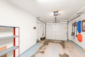 A garage with a closed door, a workbench, and shelves.