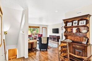 Ein geräumiges Wohnzimmer mit einem Holzkabinett, einem Fernseher und einem Kamin.