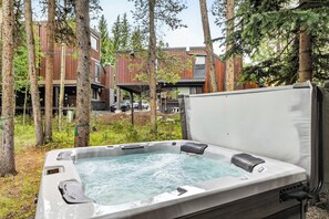 Ein Whirlpool in bewaldeter Landschaft, im Hintergrund ein modernes Gebäude.