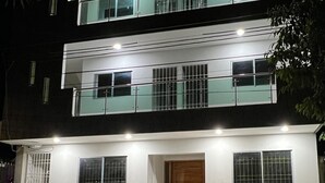 Un edificio moderno de dos pisos con balcón, ventanas grandes y puerta de madera.