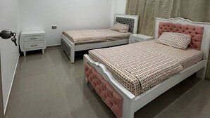 Un dormitorio con dos camas, un ventilador de techo y una ventana con cortinas.
