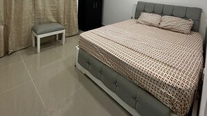 Un dormitorio con cama, banca, armario y ventilador de techo.