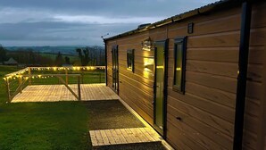 Un bâtiment en bois doté d’une terrasse dallée et d’un chemin de gravier menant à l’entrée.