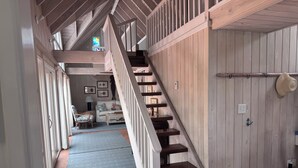A wooden staircase leading to a loft bedroom with a view of the living area below. - Spinney Dune-Beachfront Cottage in the Heart of Hope Town With Harbour Views (Hope Town)