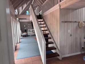 A wooden staircase leading to a loft bedroom with a view of the living area below.