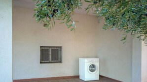 A laundry room with a washing machine, a window with bars, and a tiled floor.