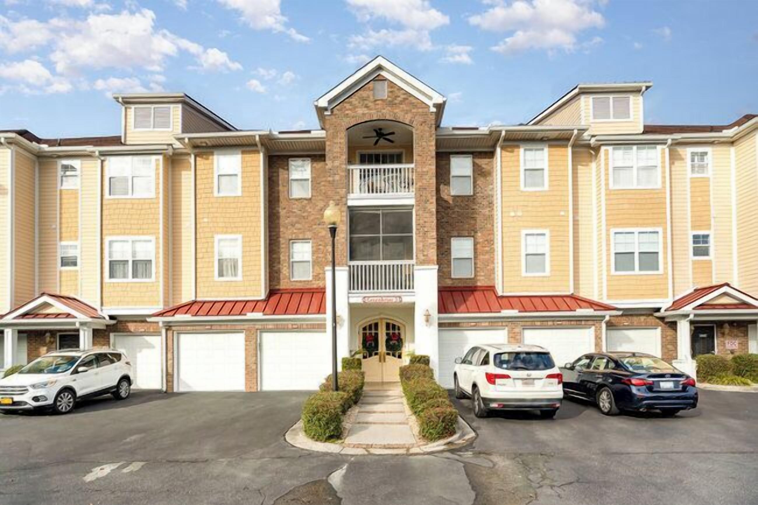 A multi-story residential building with a central entrance, a balcony, and a garage.