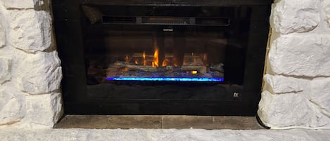 Ein Kamin aus Stein mit Glasfront, in dem ein Feuer brennt.