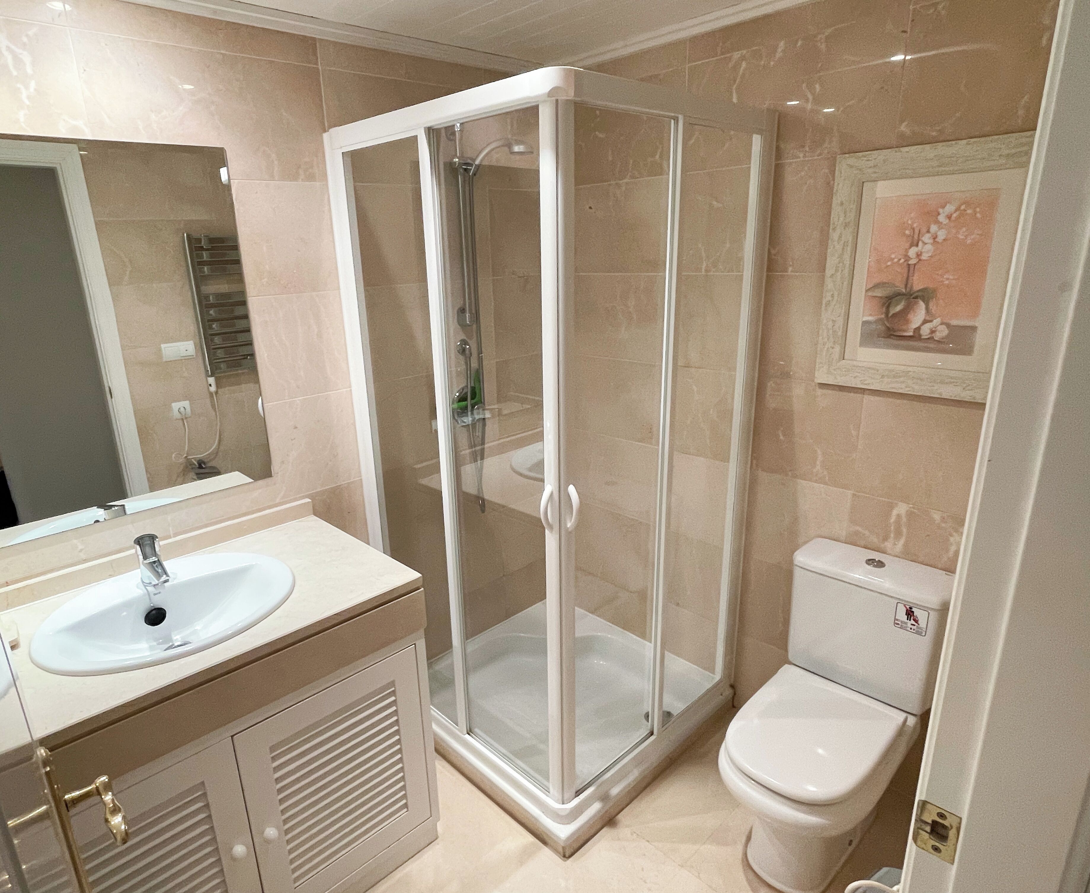 Un baño moderno con ducha de vidrio, lavamanos y retrete.
