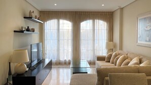 A modern living room with a sofa, a coffee table, a TV, and a lamp.